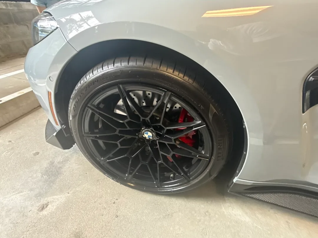 2024 BMW M3 gloss black M wheel close-up with red brake caliper detail